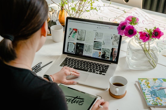 woman is working at the desk with her laptop